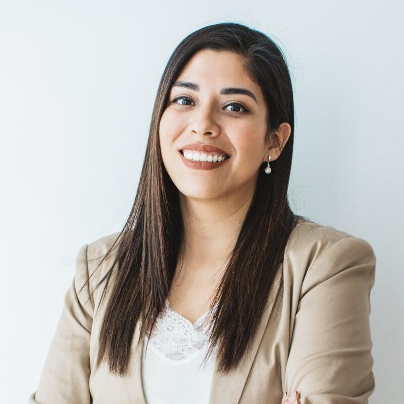 a smiling woman with long dark hair wearing a beige blazer and white blouse, captioned ‘BuzzFeed’
